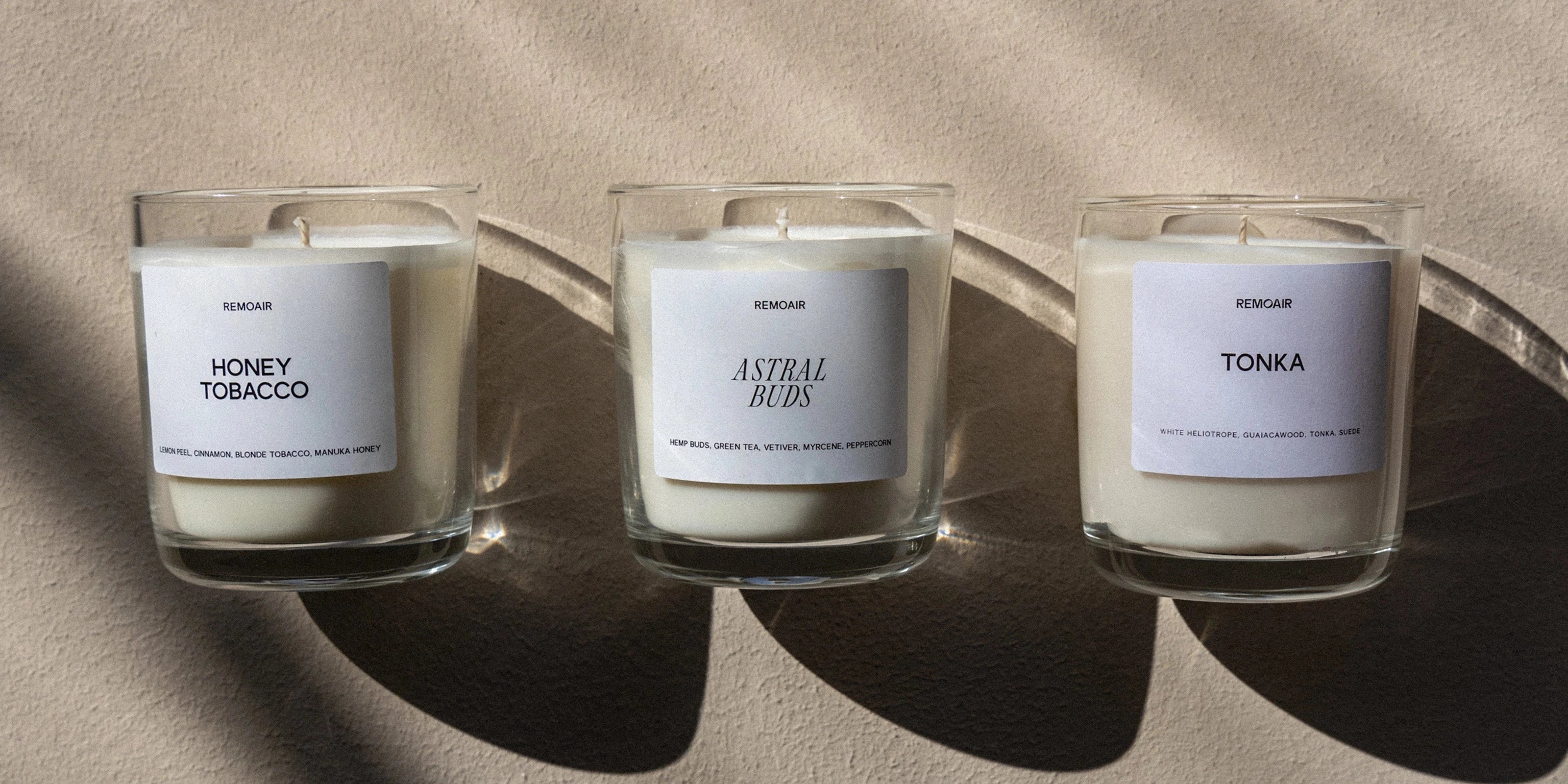 Tre av Remoairs veganska doftljus står uppradade på ett bord med vit bakgrund
