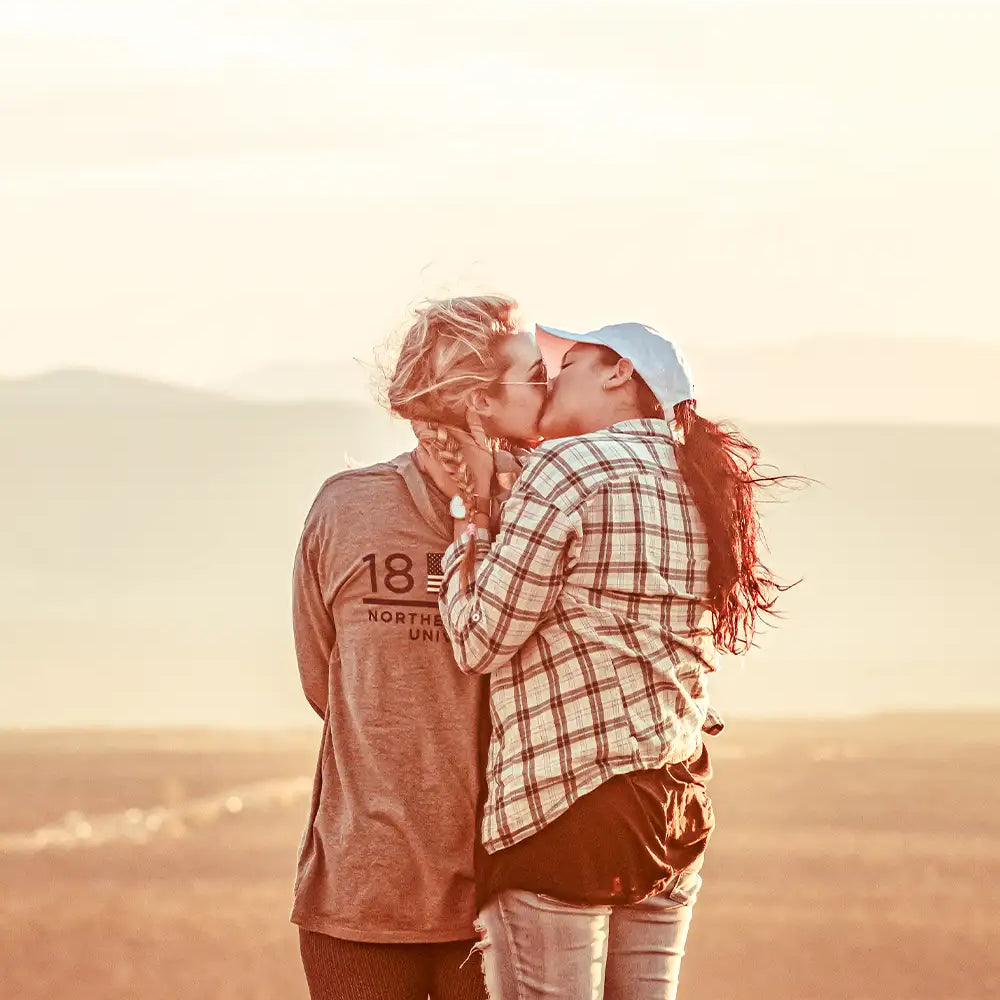 två kvinnor står bland berg och kysser varandra