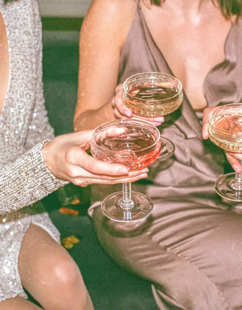 Tre glas fyllda med champagne och glittriga klänningar