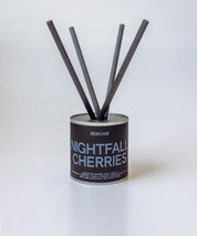 Nightfall Cherries doftpinnar i metallburk med svarta stickor ⎯ elegant och minimalistisk studiomiljö.