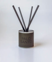 Palo Santo doftpinnar i metallburk med svarta fiberstickor ⎯ avbildade i enkel ljus miljö.