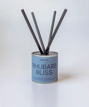 Rhubarb Bliss doftpinnar i metallburk med svarta fiberstickor ⎯ centrerad bild på ljus neutral bakgrund.