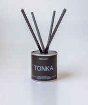 Tonka doftpinnar i metallburk med svarta fiberstickor ⎯ centrerad produktbild mot ljus bakgrund.