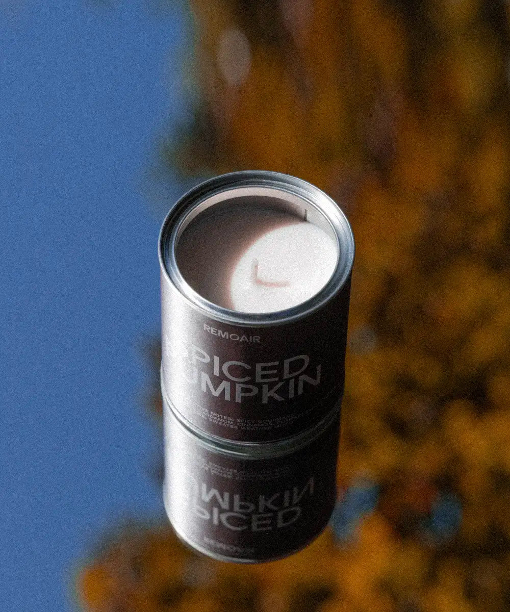 Spiced Pumpkin doftljus i en metallbehållare ståendes på en spegel med reflektion av höstlöv och blå himmel.