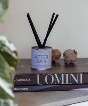 Närbild på After Rain doftburk med ljusblå detalj, svart lock och korta lyxiga stickor.