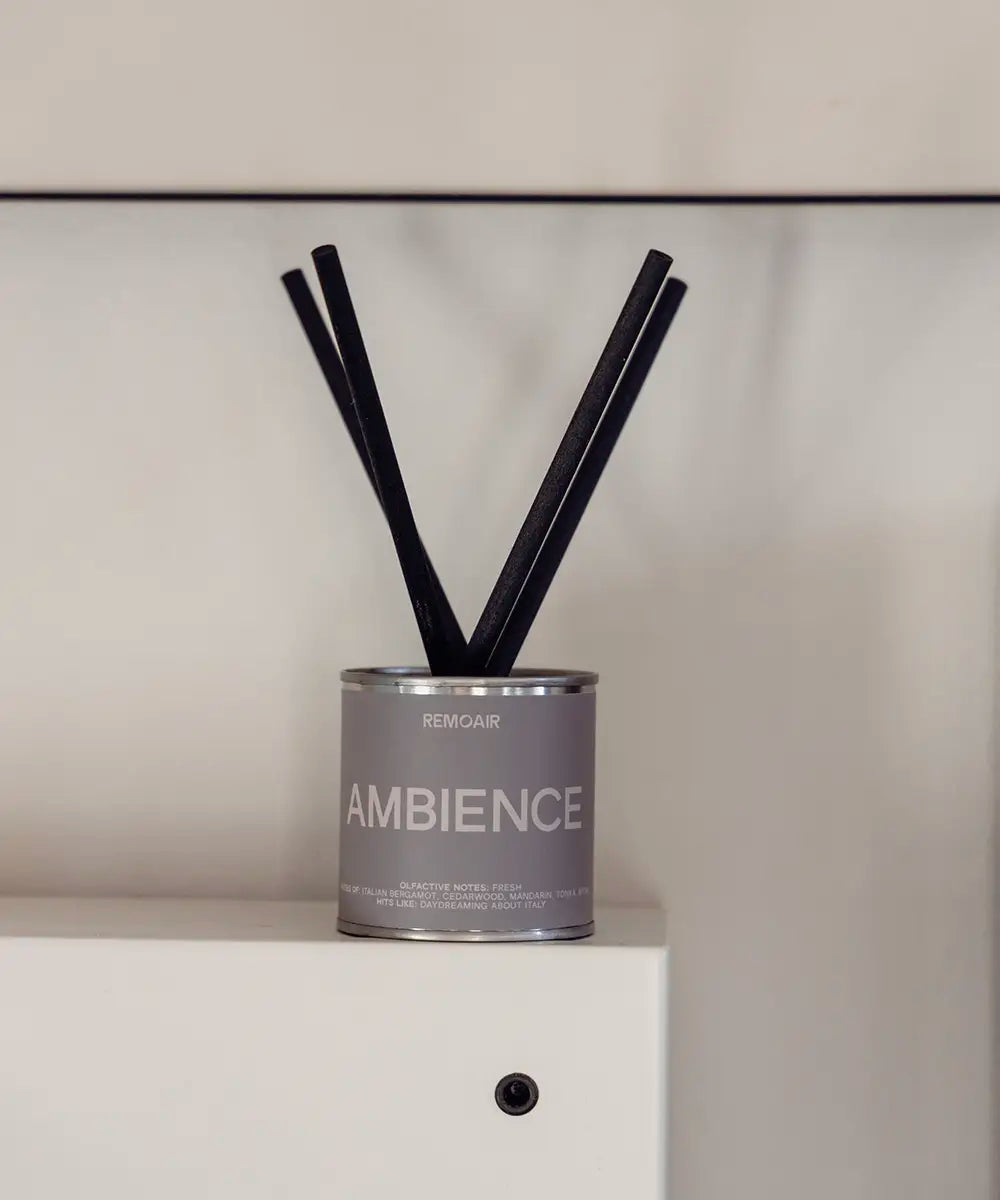 Lyxiga doftpinnar Ambience i silver plåtburk med korta svarta stickor på en vit inredningsdetalj.