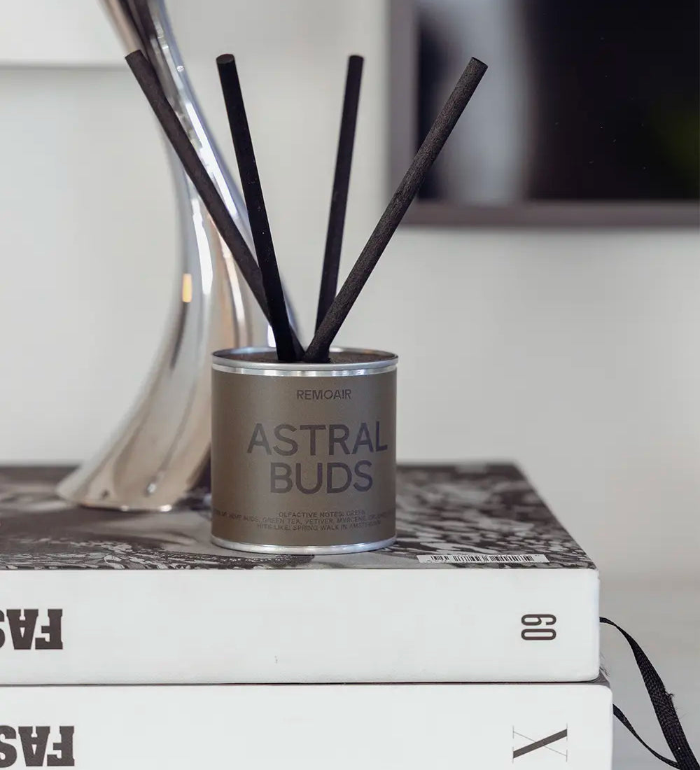 Astral Buds doftset i stilren silverbehållare placerad på inredningsböcker.