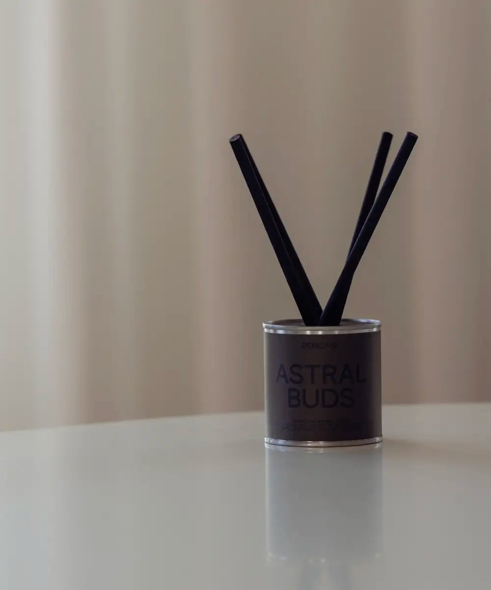 Minimalistiska Astral Buds doftpinnar med mossgrön etikett på en ren vit yta.