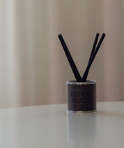 Minimalistiska Astral Buds doftpinnar med mossgrön etikett på en ren vit yta.