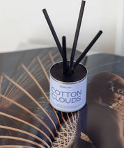 Cotton Clouds doftpinnar i silver plåtburk med korta svarta stickor i ljus inredning.