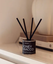 Miljövänligt doftset Honey Tobacco med korta svarta stickor i en minimalistisk skandinavisk miljö.