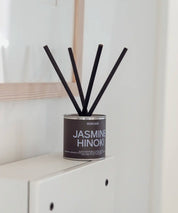 Närbild på Jasmine Hinoki doftset med mörkbrun etikett, svart lock och korta lyxiga stickor.