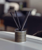 Lyxiga doftpinnar Lavender Crush med mossgrön detalj och svart lock på ett sidobord.