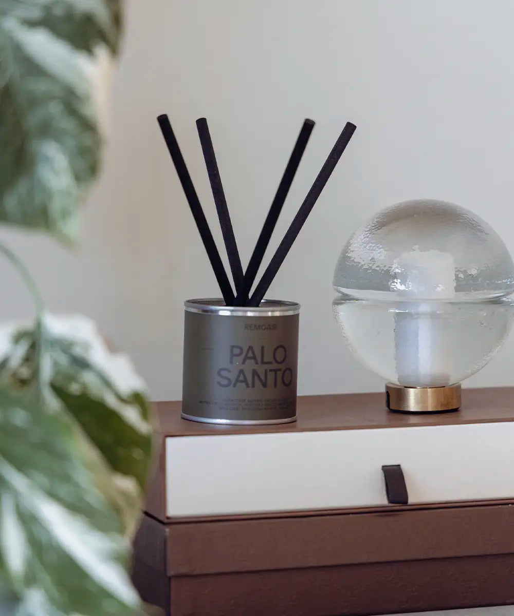 Miljövänligt doftset Palo Santo i stilren silverbehållare med mossgrön detalj på ett bord