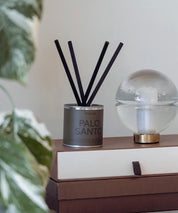 Miljövänligt doftset Palo Santo i stilren silverbehållare med mossgrön detalj på ett bord