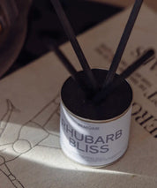 Närbild på Rhubarb Bliss doftpinnar med svart lock och sober ljusblå etikett.