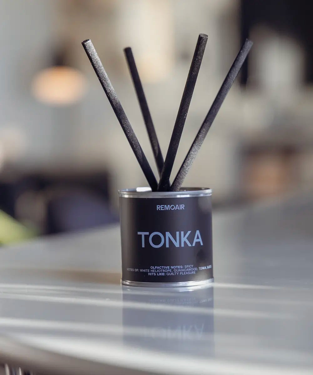 Tonka doftspridare med ljusblå text och korta svarta stickor i en modern inredning.