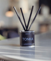 Tonka doftspridare med ljusblå text och korta svarta stickor i en modern inredning.