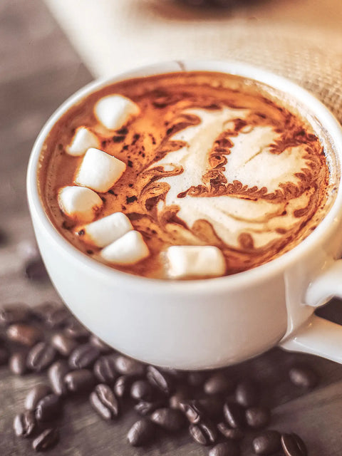 bild på kaffe latte med marshmallows, under ligger kaffebönor