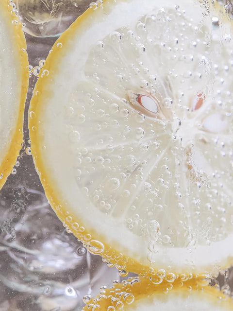 bild på citronskiva liggandes i glas med bubbelvatten fyllt med is